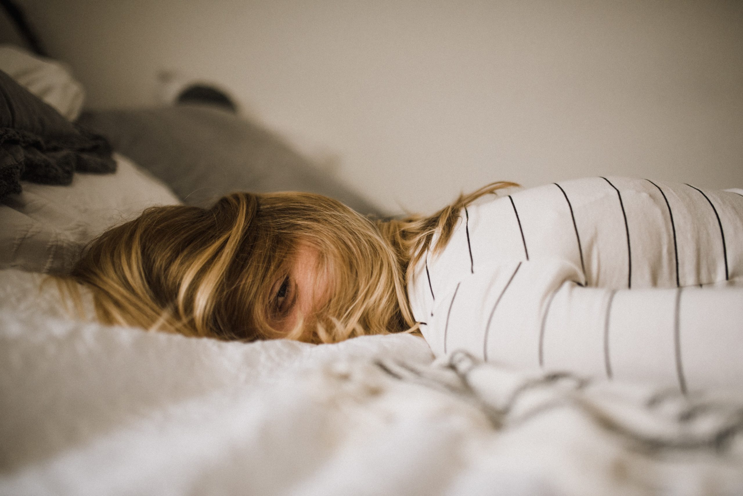 A stressed woman lying on a bed. How to stay sane during COVID-19 :: Albuquerque Moms Blog