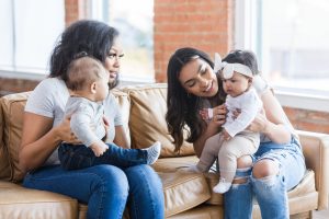 Two young mothers sit together and talk