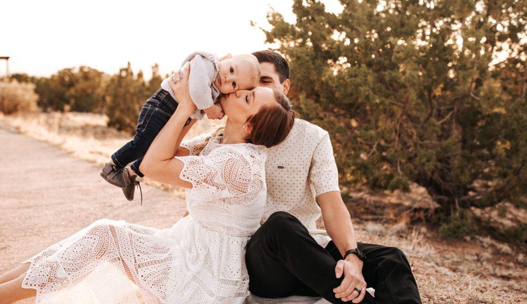 Mom lifting up baby while dad watches behind